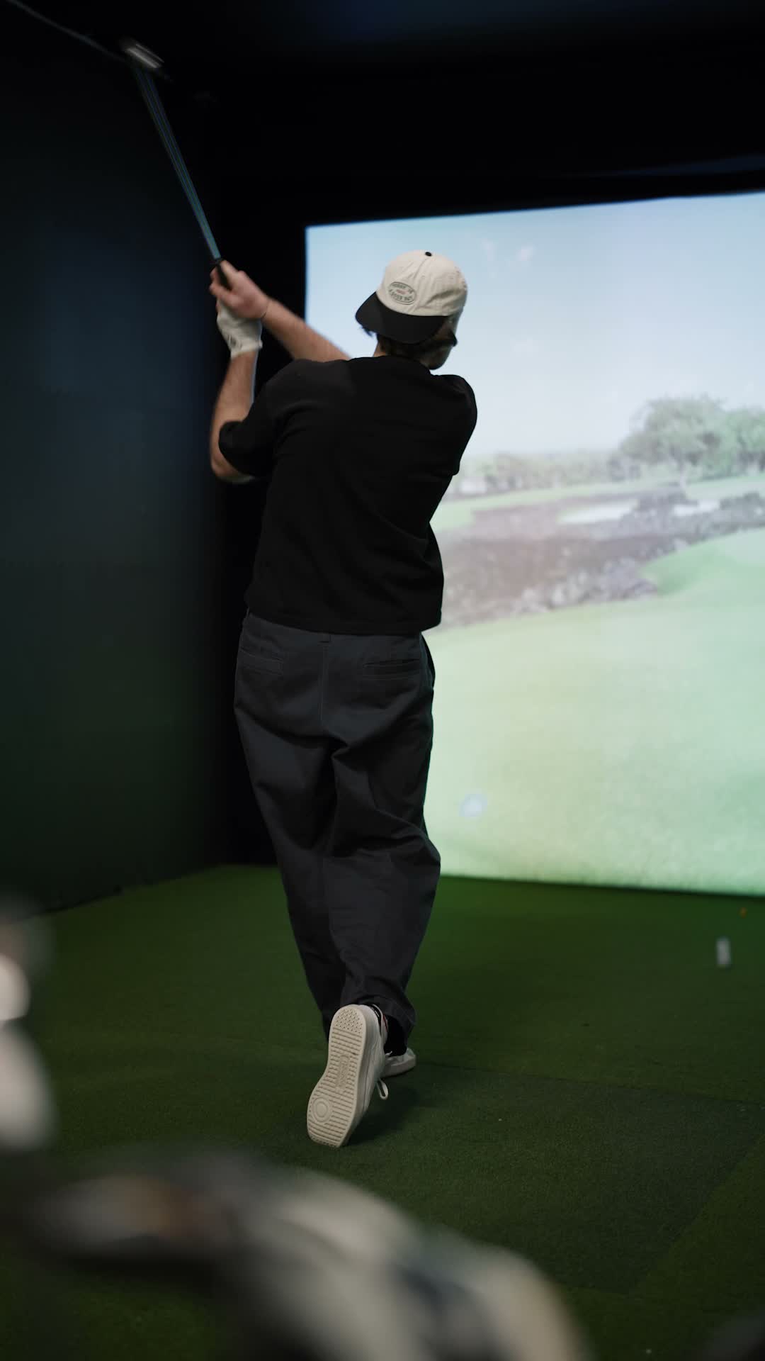 Golfeur terminant son élan devant un simulateur Trackman iO au Birdie